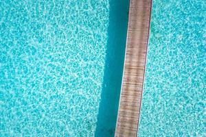 Luftdraufsicht tropische Inselbucht. hölzerne pierbrücke mit blauer lagune auf der malediveninsel, wunderschönes tropisches malediven-resorthotel. foto