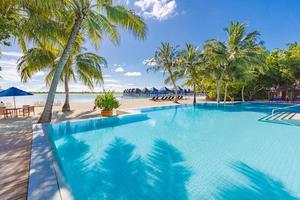 Luxus am Pool vor dem Strand. erstaunlicher Infinity-Pool mit Palmblättern unter Sonnenlicht. Tropical Paradise Island Resort oder Hotelhintergrund. luxuriöser tropischer strandurlaub oder urlaub foto