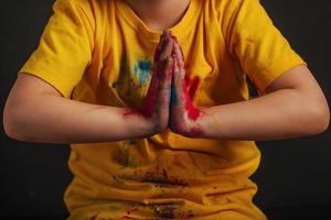Kinderhände in leuchtend bunten Holi-Farben sind in einer Namaste-Grußgeste gefaltet. Treffen Sie das indische Festival Holi foto