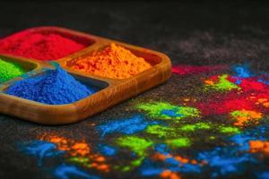 organische mehrfarbige helle farben von holi in verschiedenen farben in einer holzplatte auf dunklem hintergrund zur feier des holi-festes. foto