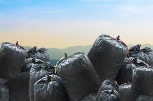 Schwarze Mülltüte isoliert auf Naturlandschaftshintergrund, Müllsack foto