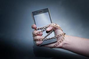 Lock Chain Smartphone Hand Woman Holding, Informationssicherheit, Sicherheit personenbezogener Daten und Schutzkonzept - Metallkettengliedhand mit gesperrtem Vorhängeschloss auf Smartphone auf dunklem Hintergrund foto