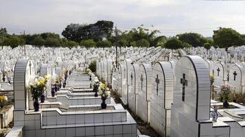 Der öffentliche Friedhof enthält identische weiße Keramikgräber mit Blumen. foto