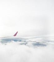 Flugzeugflügel, der über einem dramatischen Himmel mit weißen Wolken aus großer Höhe fliegt. aus dem Flugzeugfenster gesehen. foto