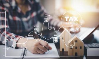 Konzept Steuerzahlungsoptimierung Unternehmensfinanzierung, Holzhaus mit Steuersymbol auf dem Technologiebildschirm, Einkommenssteuer und Eigentum, Geschäftspersonen und Unternehmen wie Mehrwertsteuer foto