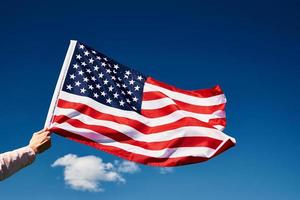 US-Flagge in der Hand gegen den blauen Himmel schwenken foto