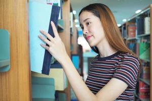 highschool- oder college-studenten wählen bücher in den regalen der bibliothek aus. foto