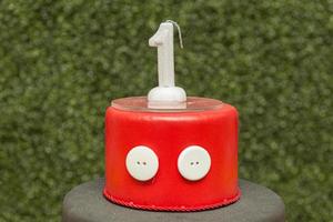 Spitze des roten gefälschten Kuchens mit einförmiger Kerze mit unscharfem grünem Hintergrund. foto