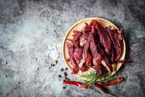 Beef Jerky mit Kräutern und Gewürzen - getrocknetes Rindfleisch auf Holzteller, rohes Trockenfleisch zum Kochen, Trockenfleisch Rindfleisch in thailändischer Küche foto