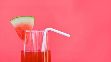 Wassermelonensaft Sommer mit Stück Wassermelonenfrucht auf Glas auf rotem Hintergrund foto