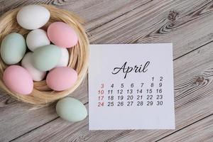 aprilkalender und osternest mit eiern in sanften pastellfarben foto