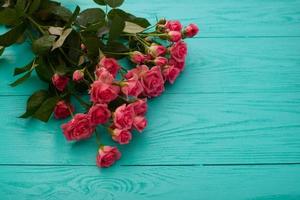 Rahmen aus bunten Rosen auf blauem Hintergrund aus Holz. Draufsicht und selektiver Fokus. Attrappe, Lehrmodell, Simulation. Platz kopieren. Blumen. Mutter Valentin foto