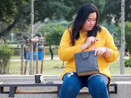 Attraktives Porträt dickes Mädchen asiatische Frau mit langen schwarzen Haaren in gelbem T-Shirt. Mit einem Lächeln in der Hand im Gartenstuhl sitzend und das recycelte Papier haltend, ist es glücklich in ein rosarotes Herz gefaltet foto