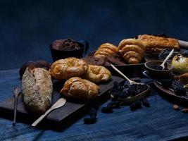 Draufsicht frisches Brot braune Rosinen Sesambäckerei aus Weizenmehl Lebensmittel hausgemacht geeignet für gesunde Ernährung auf Holztischboden schwarzer rustikaler dunkler Hintergrund foto