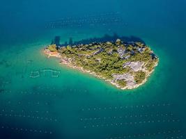 luftdrohnenansicht einer kleinen insel in der bucht von mali ston auf der halbinsel peljesac. Austernfarmen im türkisfarbenen Meerwasser. Einzigartige Mischung aus Süß- und Meerwasser. foto