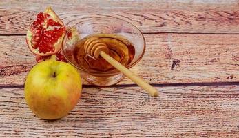 rosh hashanah jüdisches feiertags-torah-buch, honig, apfel und granatapfel über holztisch. traditionelle Symbole. foto