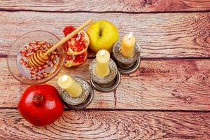 rosh hashanah jüdisches feiertags-torah-buch, honig, apfel und granatapfel über holztisch. traditionelle Symbole. foto