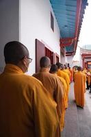 bandung, indonesien, 2020 - die mönche in orange rob stehen in ordnung, während sie zum gott am altar im buddha-tempel beten foto