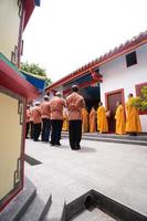 bandung, indonesien, 2020 - die mönche in orange rob stehen in ordnung, während sie zum gott am altar im buddha-tempel beten foto