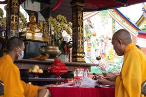 bandung, indonesien, 2020 - die mönche mit orangefarbenen gewänden setzen sich auf den stuhl und beten zum gott auf dem altar foto