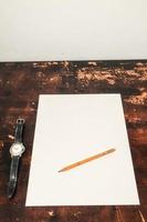 Uhr und Bleistift auf weißem Papier foto