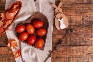 auf einem hölzernen hintergrund ostereier bemalt mit natürlichen pflanzenfarben, zwiebelschale, neben einem hölzernen osterhasen und einer weide, draufsicht, kopierraum foto