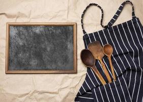 leerer quadratischer Holzrahmen und blaue Kochschürze foto