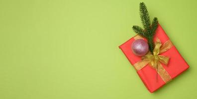 Rote Geschenkbox mit rotem Band auf grünem Hintergrund, Draufsicht. festliche Kulisse foto