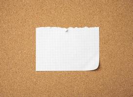 leeres blatt papier, das mit einem knopf auf einer braunen korkplatte festgehalten wird foto