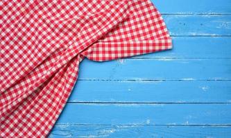 gefaltete Küchenserviette aus roter und weißer Baumwolle auf einem hölzernen blauen Hintergrund foto