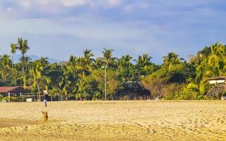 Sonne Strand Sand Menschen Wellen Palmen in Puerto Escondido Mexiko. foto