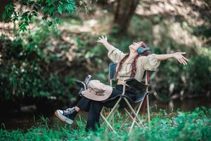 junge asiatische frau, die auf stuhl sitzt und musik vom kopfhörer hört foto