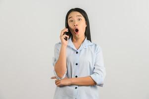 Porträt einer jungen asiatischen Frau, die am Handy spricht, während sie isoliert über weißem Hintergrund steht foto