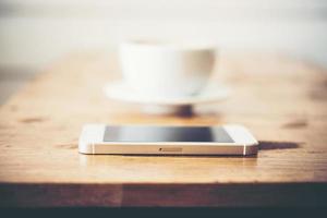 eine Tasse Kaffee und Smartphone auf Holztisch im Café foto