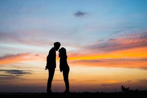 Silhouette des jungen Paares zusammen während des Sonnenuntergangs foto