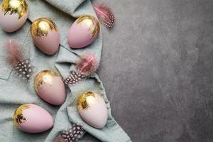Ostereier sind mit violetter und goldener Farbe auf grauem Leinengrund bemalt. foto