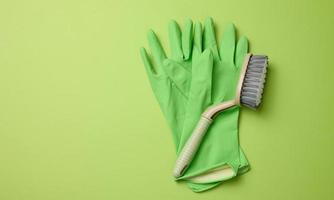 Grün Gummi Handschuhe zum Reinigung, Bürsten auf ein Grün Hintergrund foto