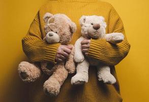 Frau im Orange gestrickt Sweatshirt Umarmungen süß braun Teddy tragen. das Konzept von Einsamkeit und Traurigkeit, Depression foto