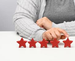 Kundenerlebnis-Feedback-Konzept. Fünf rote Sterne, die Bestnote exzellente Leistungen mit weiblicher Hand zu erfüllen. weißer Tisch foto