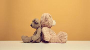 zwei süß braun Teddy Bären Sitzung auf ein Gelb Hintergrund, Kinder Spielzeug foto