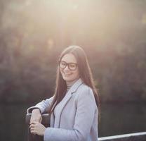 Frau im Mantel lächelt beim Sonnenuntergang foto