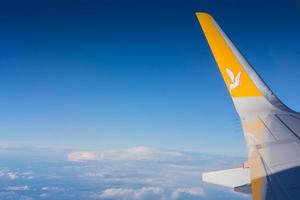 Flügel von ein Flugzeug mit tief Blau Himmel und Wolken während ein Flug foto