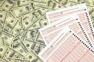 Rosa Glücksspielblätter mit Zahlen zum Markieren auf großen Hundert-Dollar-Scheinen. lotteriespielkonzept oder spielsucht. Nahansicht foto