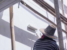 ein arbeiter streicht die wände des hauses mit einer grundierung mit einer farbrolle. foto