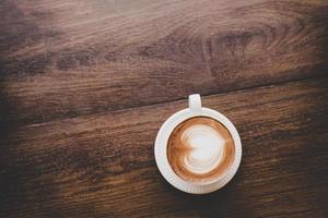 Draufsicht des Weinlese-Latte-Kunstkaffees mit Herzform auf Holztisch