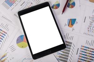 Tablet mit leerem Bildschirm über Business-Charts foto