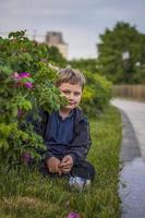 Porträt von ein Kind, ein Junge gegen das Hintergrund von Pflanzen im ein Open-Air Park. Kinder, Reise. Lebensstil im das Stadt. Center, Straßen. foto