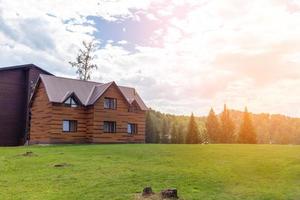 Zweistöckiges Holzhaus mit Fenstern Natur mit grünem Rasen. Verkauf oder Kauf von neuen Häusern. ein Hotel für Touristen. foto