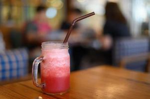 rotes Wasser in einem Glas gemischt, auf einen Holztisch gestellt foto