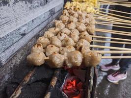 gegrillte Fleischbällchen. traditionelles straßenessen in indonesien, wo der herstellungsprozess auf heißer holzkohle gegrillt wird foto